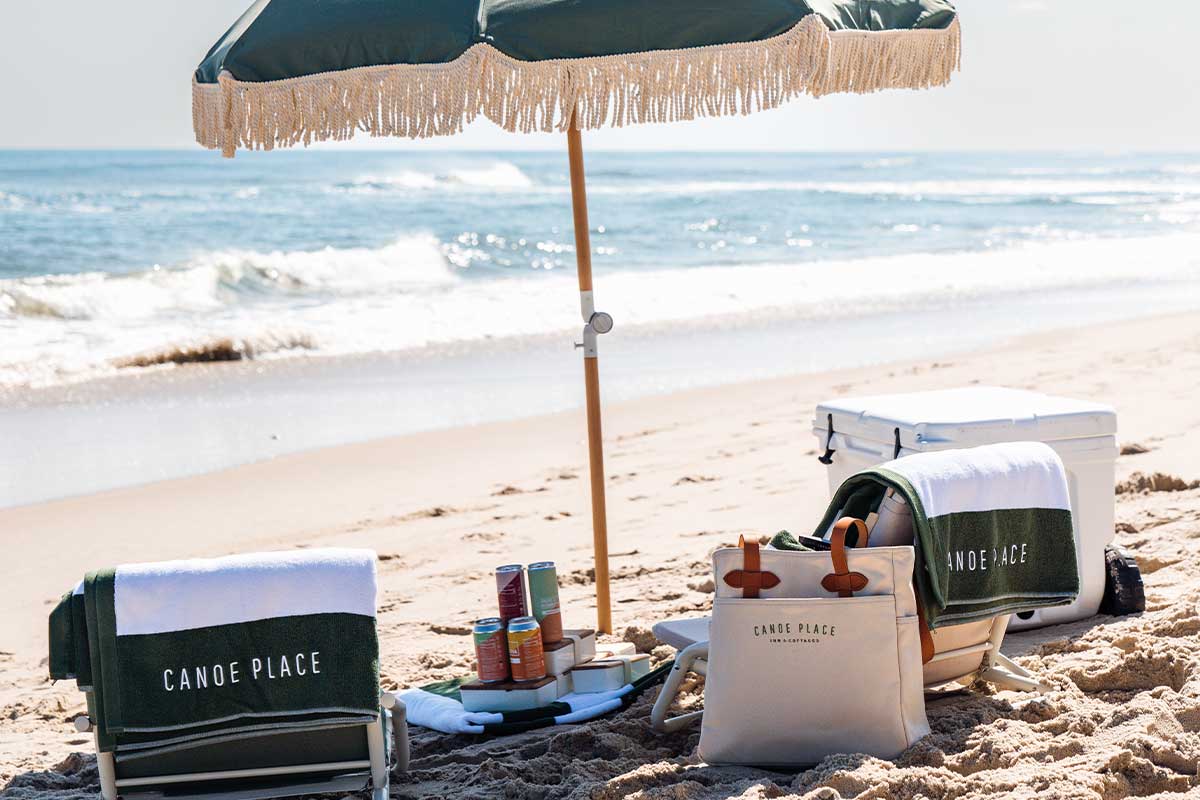 Beach area with Canoe Place towels, bag, and umbrella