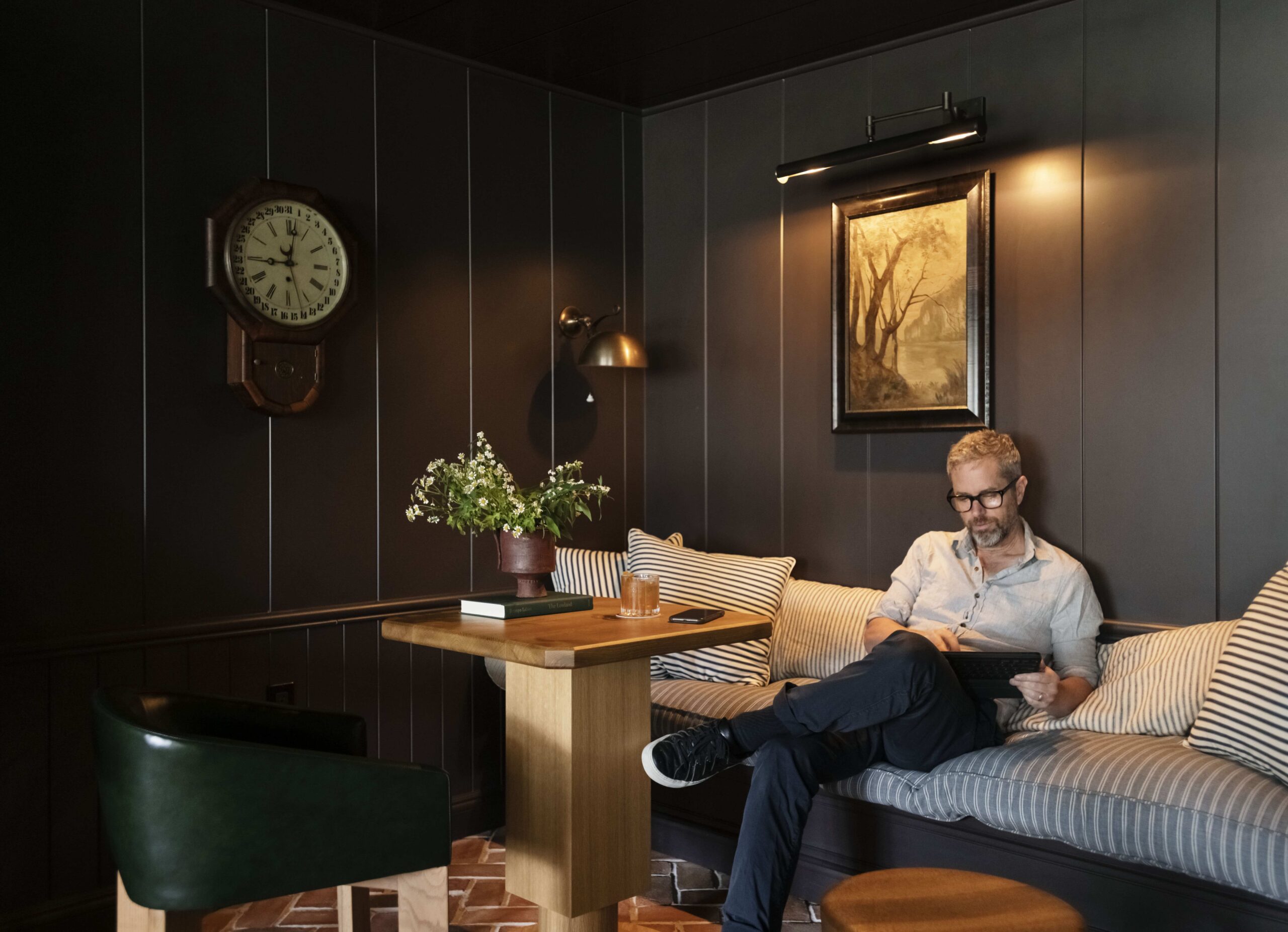 Man on iPad working in a private corner with drink