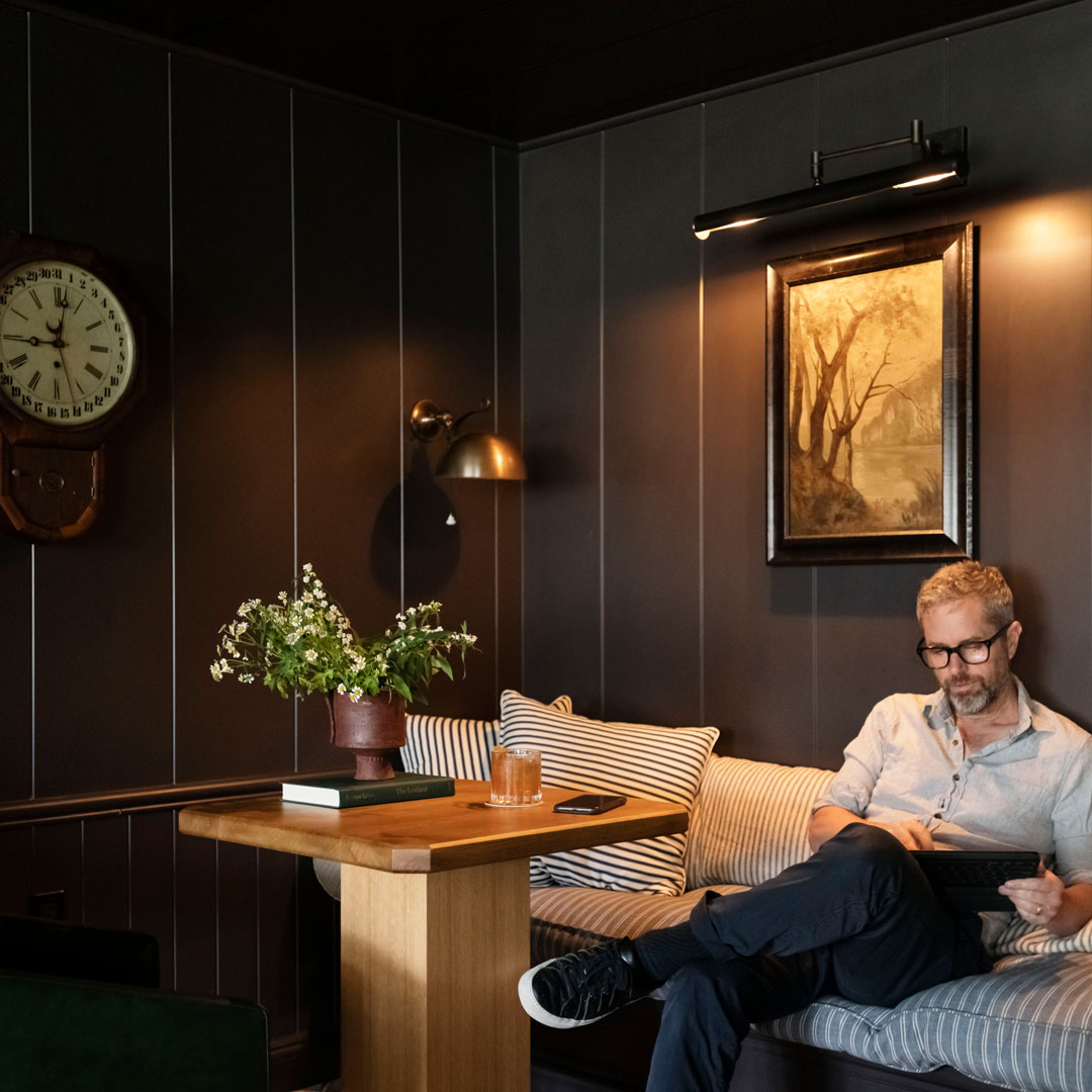 Man on his iPad in cozy corner with a drink